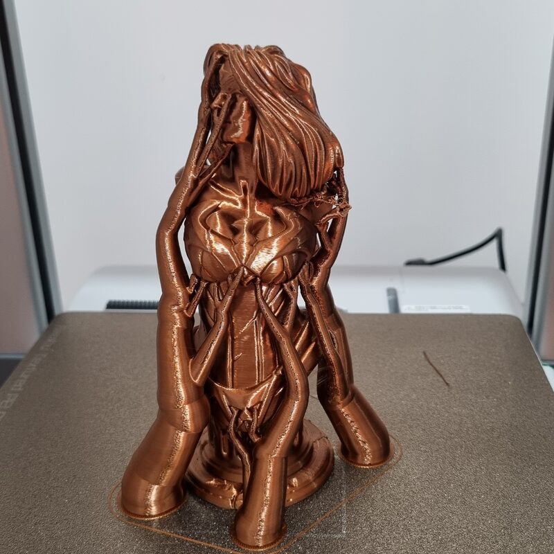 Busto decorativo impresso em filamento cor de cobre, pronto, sobre a mesa de impressão