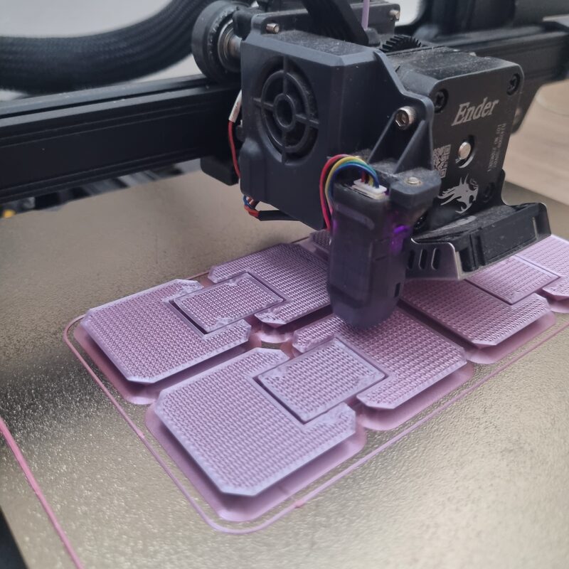 Cubo infinito impresso em filamento rainbow, ainda sobre a mesa da Creality Ender 3, com o extrusor logo acima